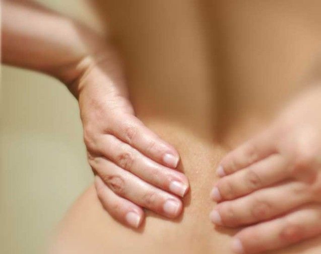 Photo of a person's hands holding their lower back